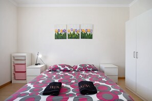 A bedroom with a bed, nightstands, a wardrobe, and a wall-mounted painting.