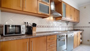 Une cuisine avec des meubles de rangement en bois, un four à micro-ondes, un lave-vaisselle et une cuisinière.