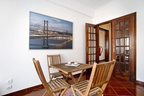 Un comedor con una mesa y sillas, un cuadro con una imagen de un puente, y una puerta de madera con paneles de vidrio.