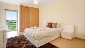 Een slaapkamer met een bed, nachtkastjes, een kledingkast en uitzicht op een groen landschap.