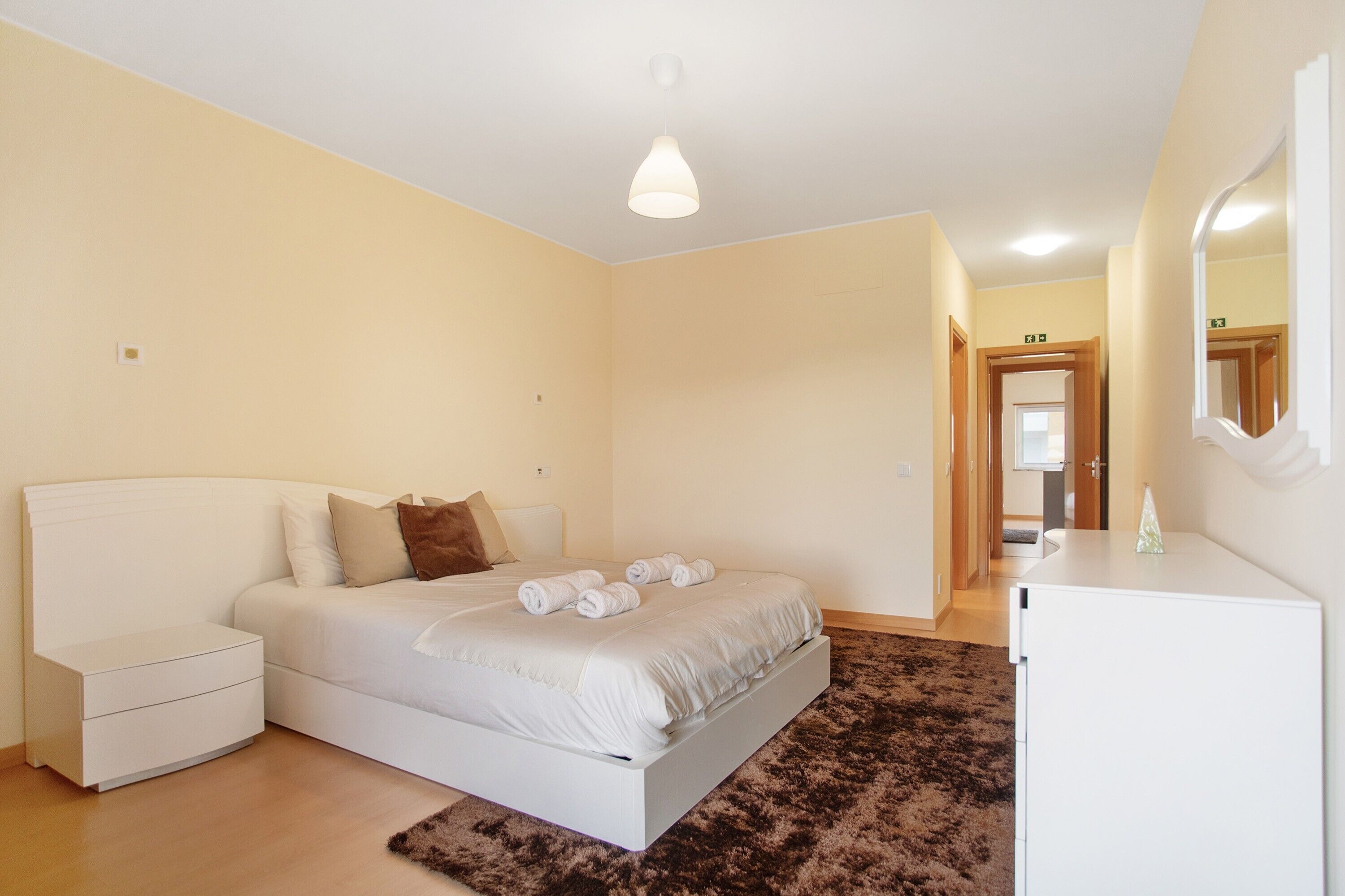 A bedroom with a bed, bedside table, and a small white cabinet.