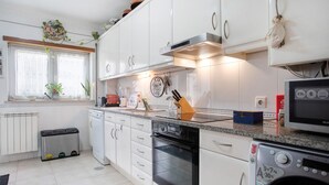 A modern kitchen with white cabinets, a built-in oven, a microwave, and a dishwasher. - Apartment 'Casa Da Mãe Maria' with Sea View, Shared Terrace and Wi-Fi (Buarcos)