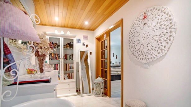 A room with a white vanity, a mirror, a decorative wall piece, a wooden door, and a small stool. - Apartment 'Casa Da Mãe Maria' with Sea View, Shared Terrace and Wi-Fi (Buarcos)