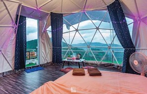 A cozy tent room with a bed, a table with items, and a view of the outdoors. -  Ahcnng Camp (Mae Rim)