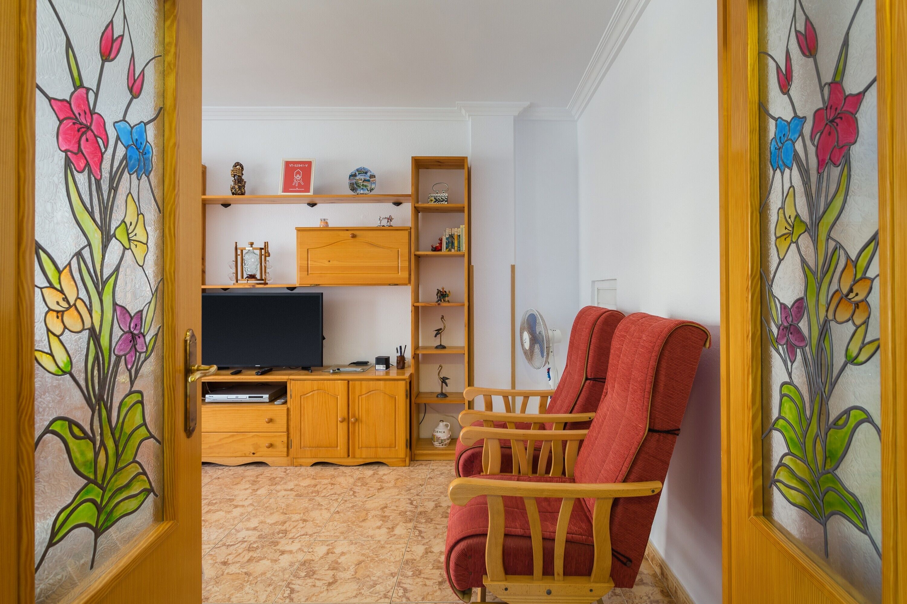 Una sala de estar con una unidad de entretenimiento de madera, una silla roja y un televisor.