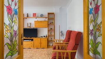 Una sala de estar con una unidad de entretenimiento de madera, una silla roja y un televisor.