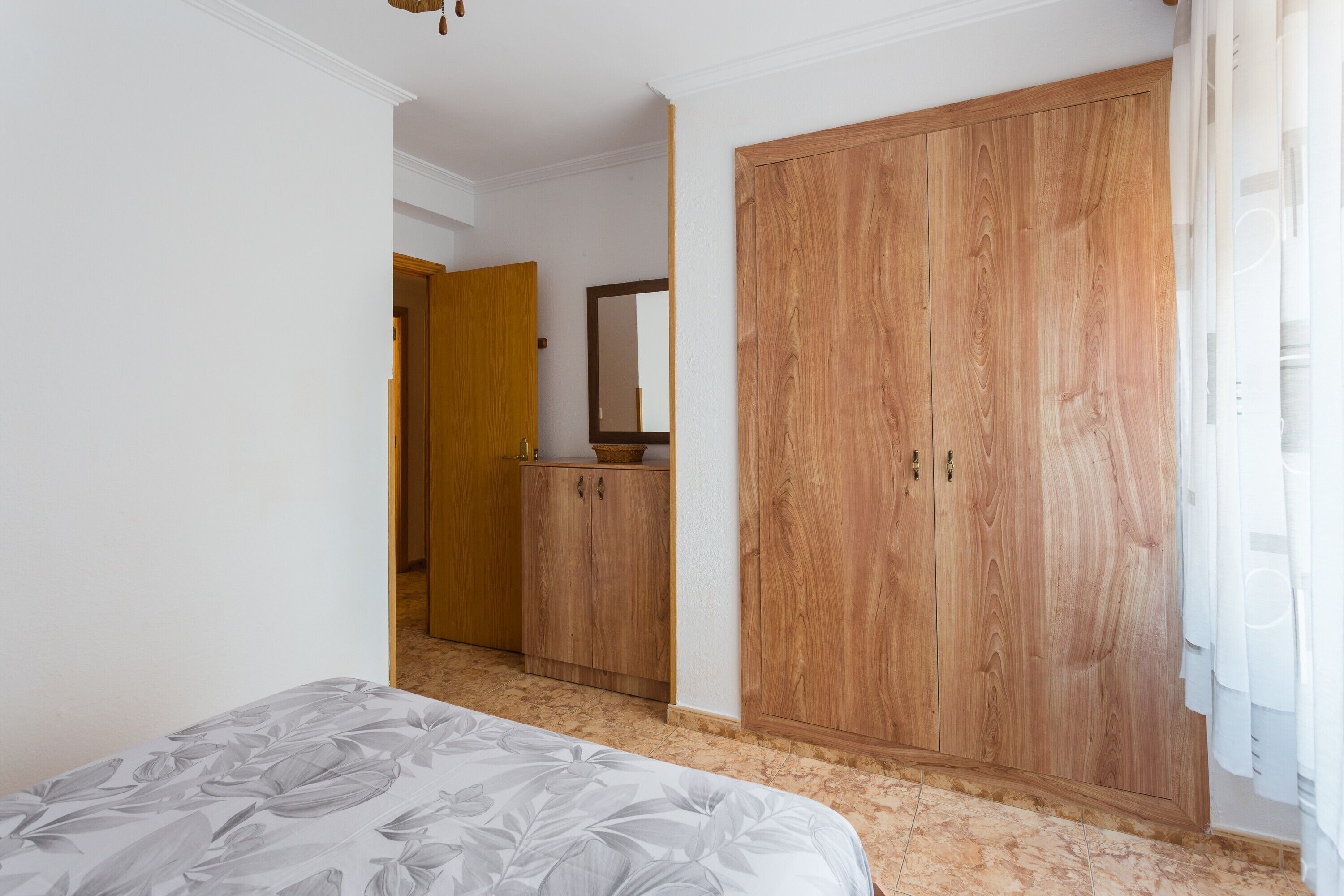 Un dormitorio con cama, armario y espejo.