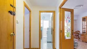 A hallway with wooden doors, a kitchen in the background, and a cabinet with glass doors. - Apartment 'Bonanza' with Private Terrace and Wi-Fi (Gandia)