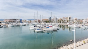 A marina with multiple boats docked, a clear sky, and buildings in the background. - Apartment 'Bonanza' with Private Terrace and Wi-Fi (Gandia)