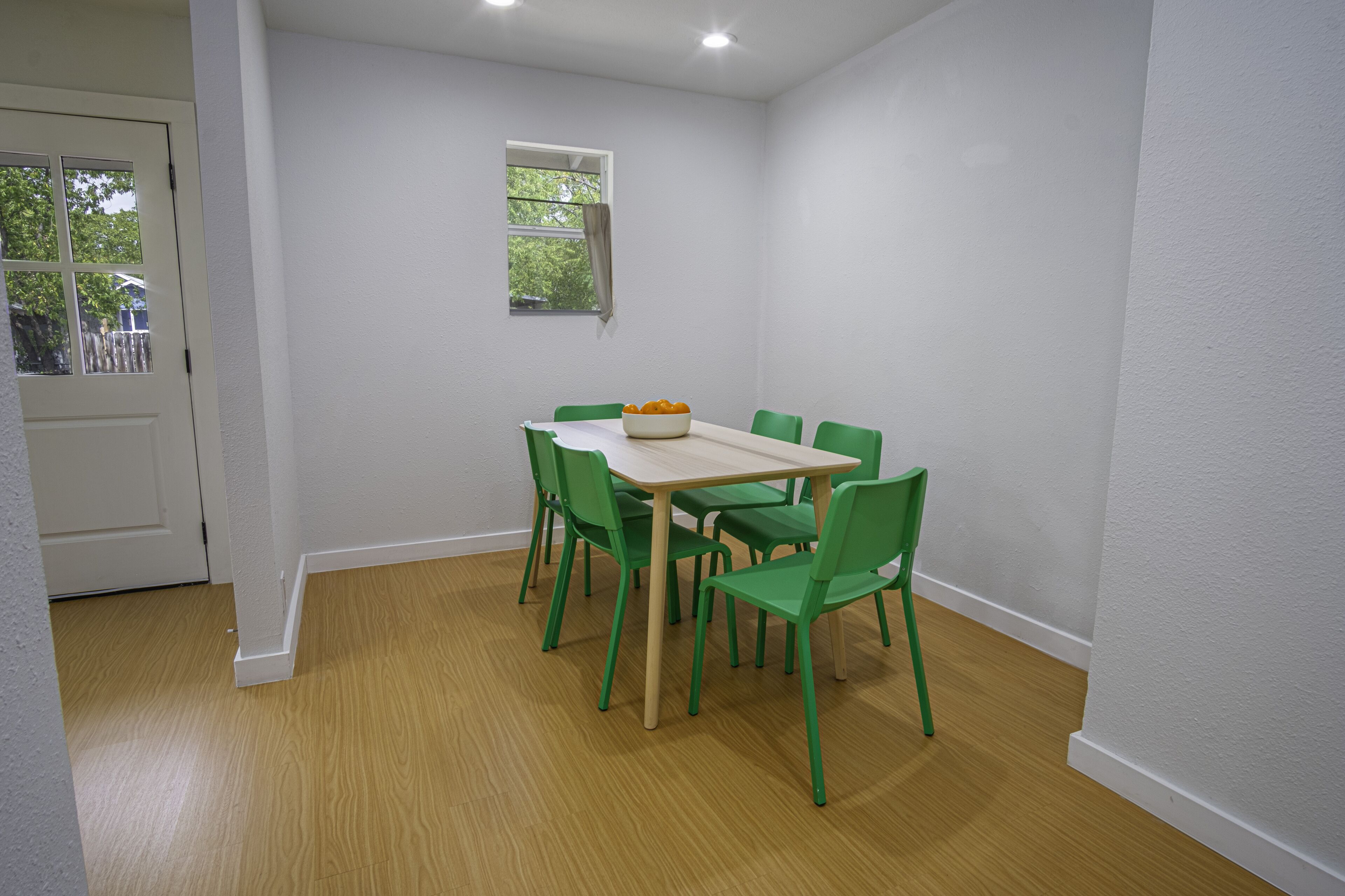 A dining area with a table and chairs, a window, and a door.
