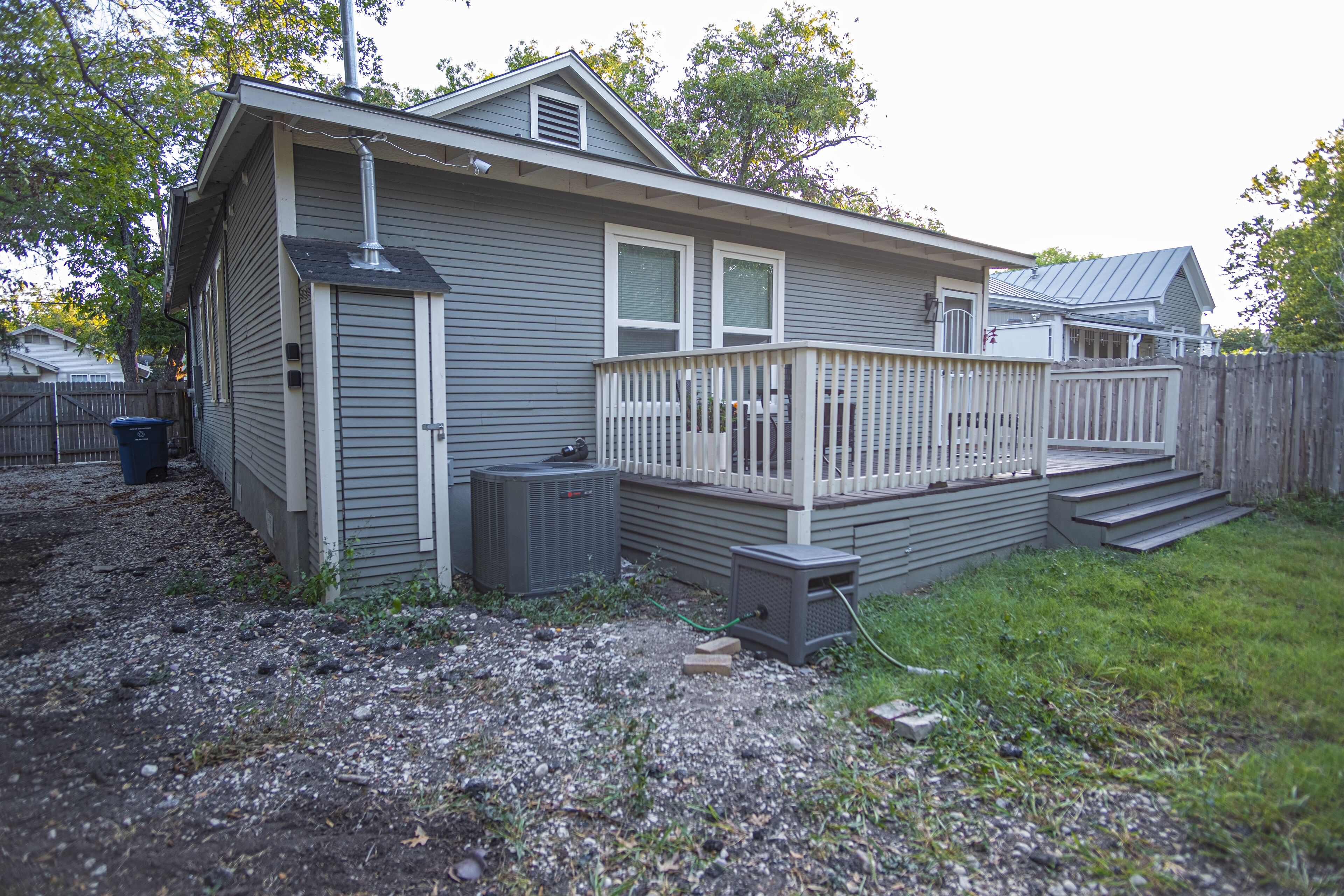 A single-story house with a front deck, a chimney, and a small shed.