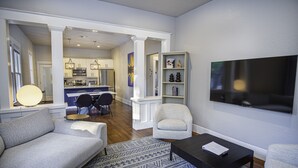 Uma sala de estar moderna com sofá, poltrona, mesa de centro e TV na parede.