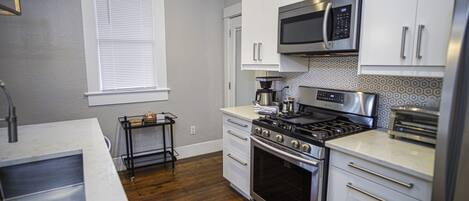 Una cocina moderna con electrodomésticos de acero inoxidable, armarios blancos y suelo de madera.