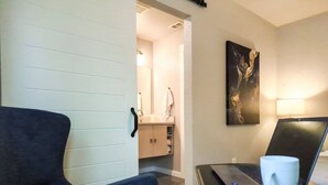 A room with a dark blue armchair, a laptop on a small table, a white mug, and a painting on the wall. - Charming Studio W/deck & Garden (San Antonio)