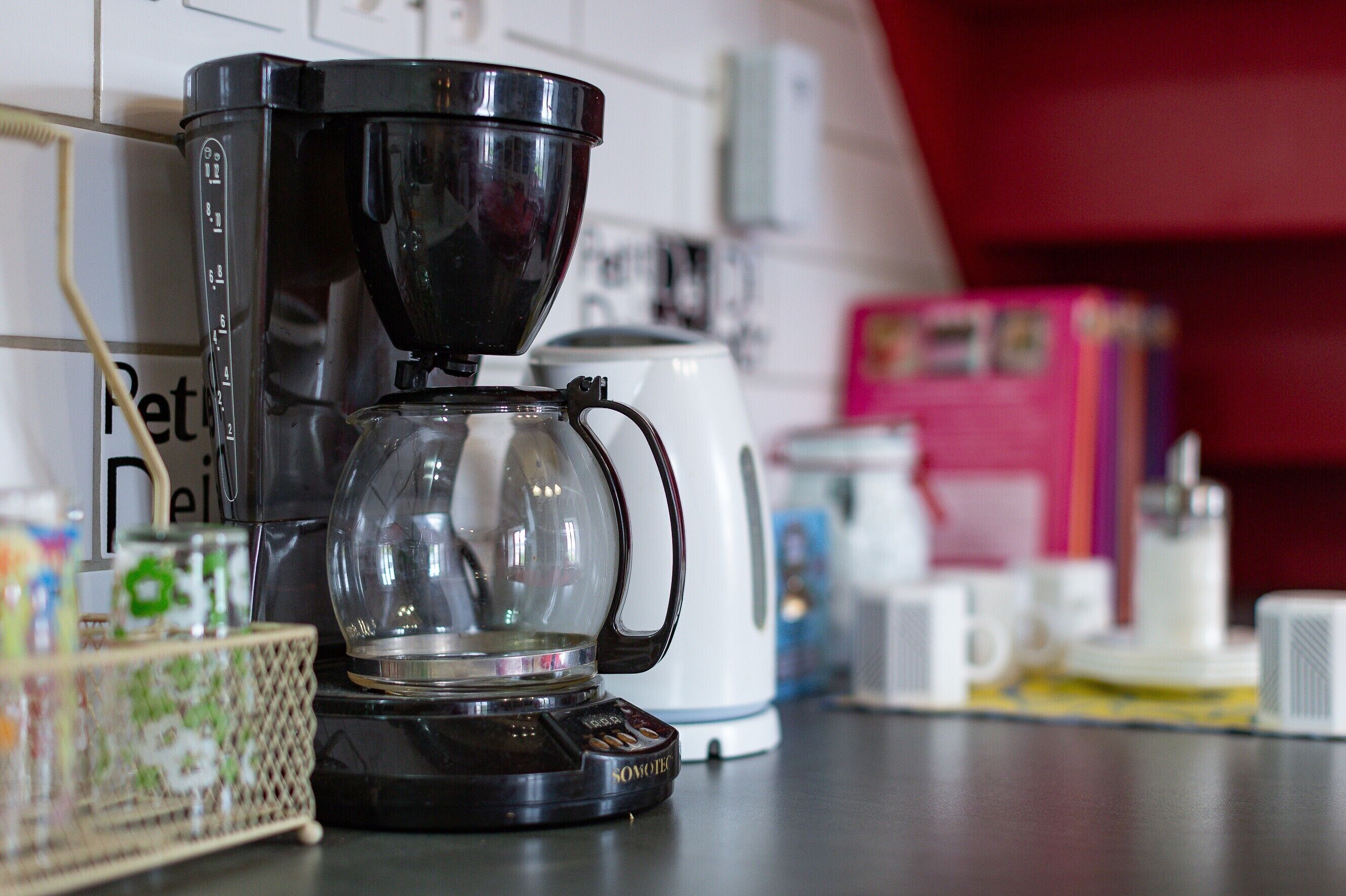 A coffee maker on a kitchen counter with a white appliance in the background.