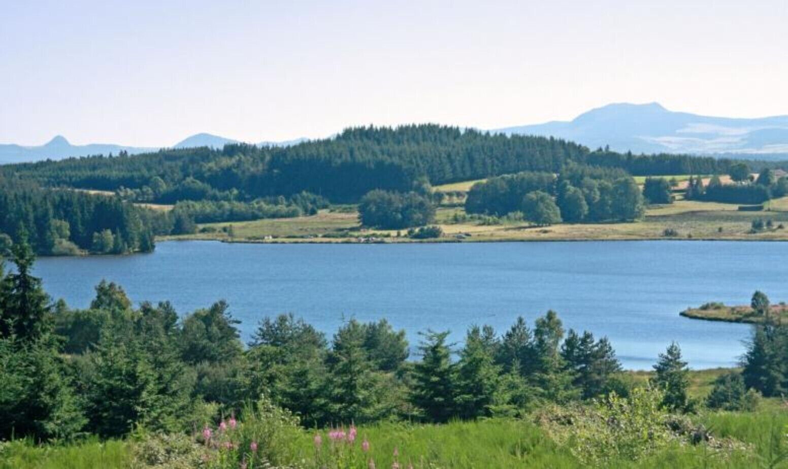 A lake surrounded by forested hills and mountains.