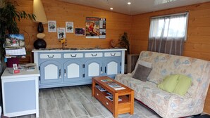 Une pièce chaleureuse avec un canapé, une armoire en bois, une petite table et une fenêtre avec des rideaux.