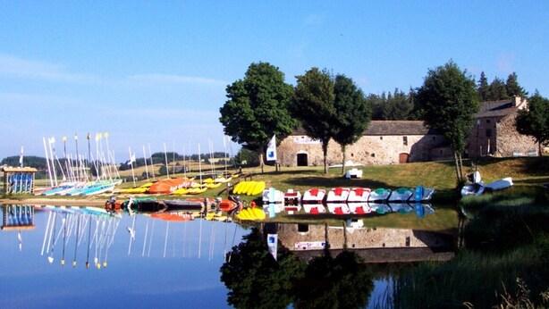 Un lac paisible avec des bateaux, un bâtiment en pierre et des arbres.