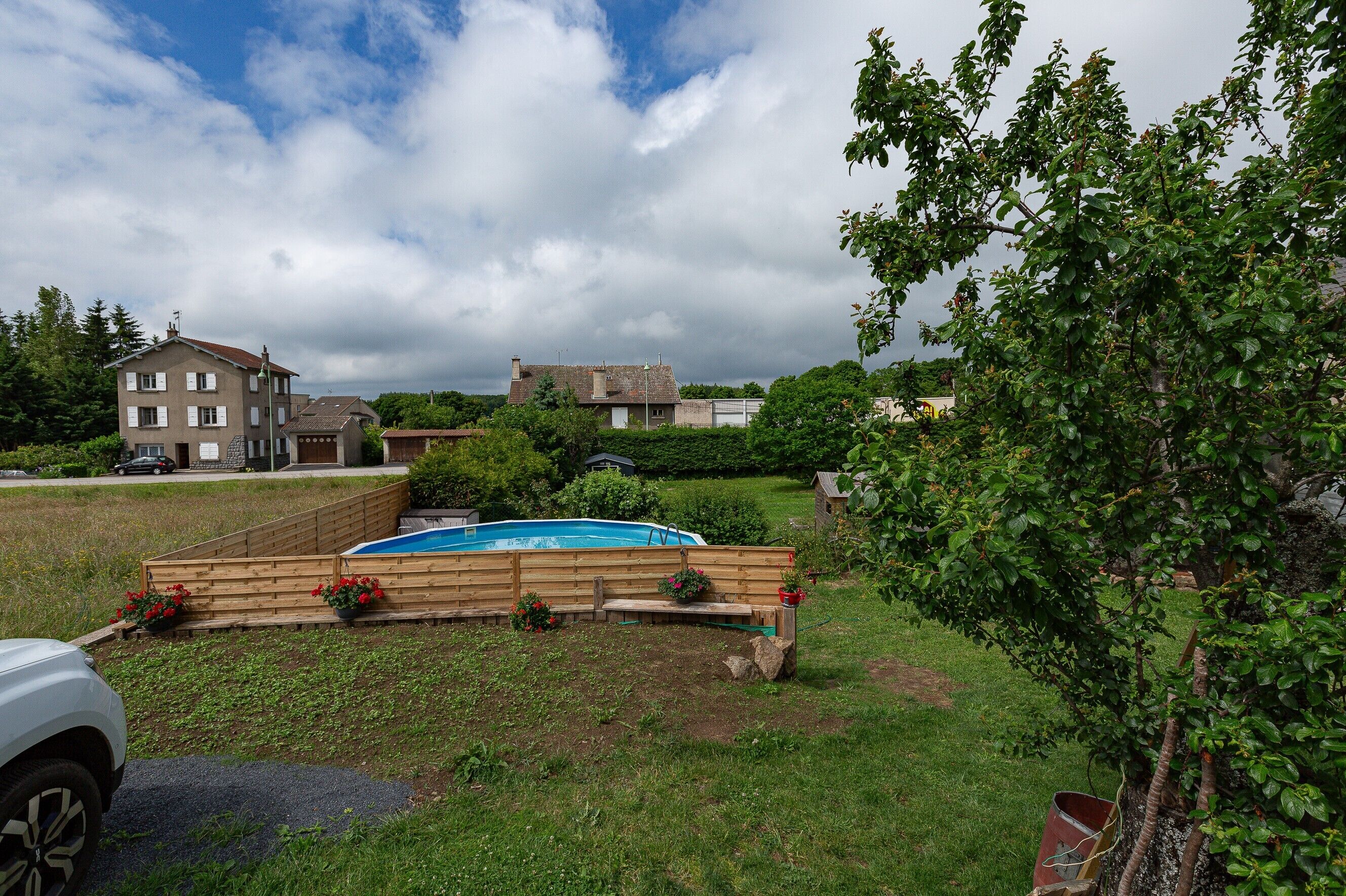 A residential area with a swimming pool, wooden deck, and a large house in the background.