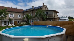 Un cadre résidentiel avec une piscine, une maison dotée d’un balcon et une voiture garée.