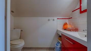 Ein Badezimmer mit Toilette, Waschbecken, Spiegel und Handtuch.