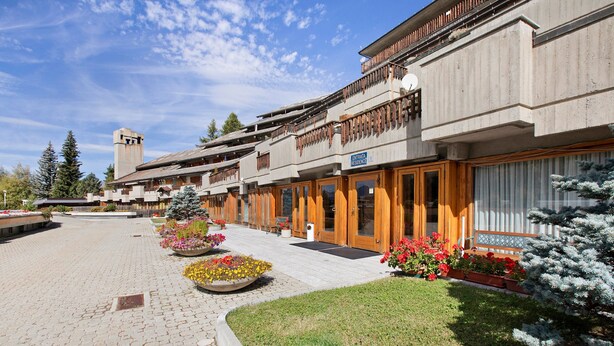 A hotel with a central courtyard, wooden balconies, and a sign indicating 'ENTRADA RESIDENCE'.