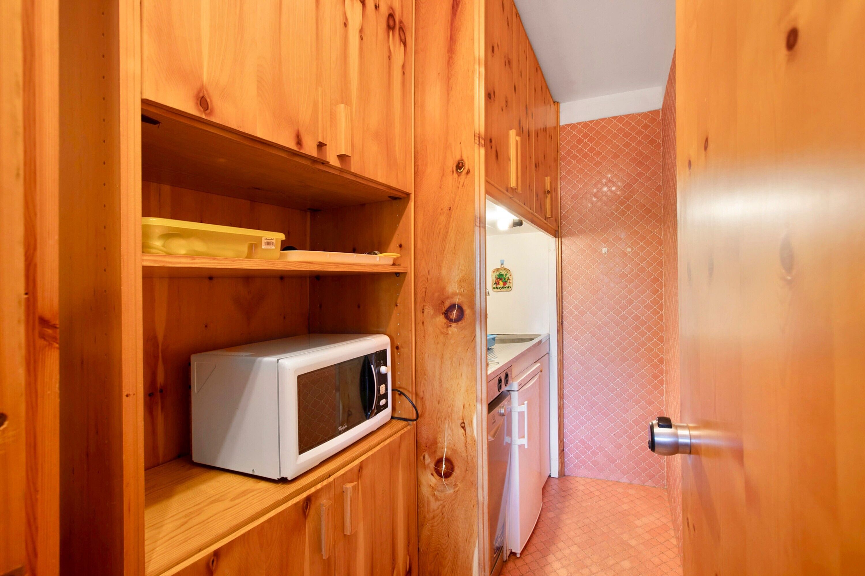 Eine kleine Küche mit Holzausstattung, einer Mikrowelle und einem kleinen Backofen.