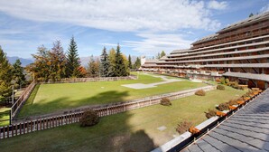A hotel with a large lawn, multiple floors, and a mountainous backdrop.
