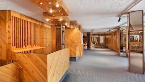 A reception area with wooden paneling, a patterned carpet, and a glass partition.