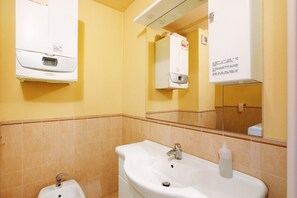 A bathroom with a sink, mirror, and towel dispenser. - Augusta Praetoria – Spacious Apartment in the Heart of Aosta, Near Pila and the Alps (Aosta)