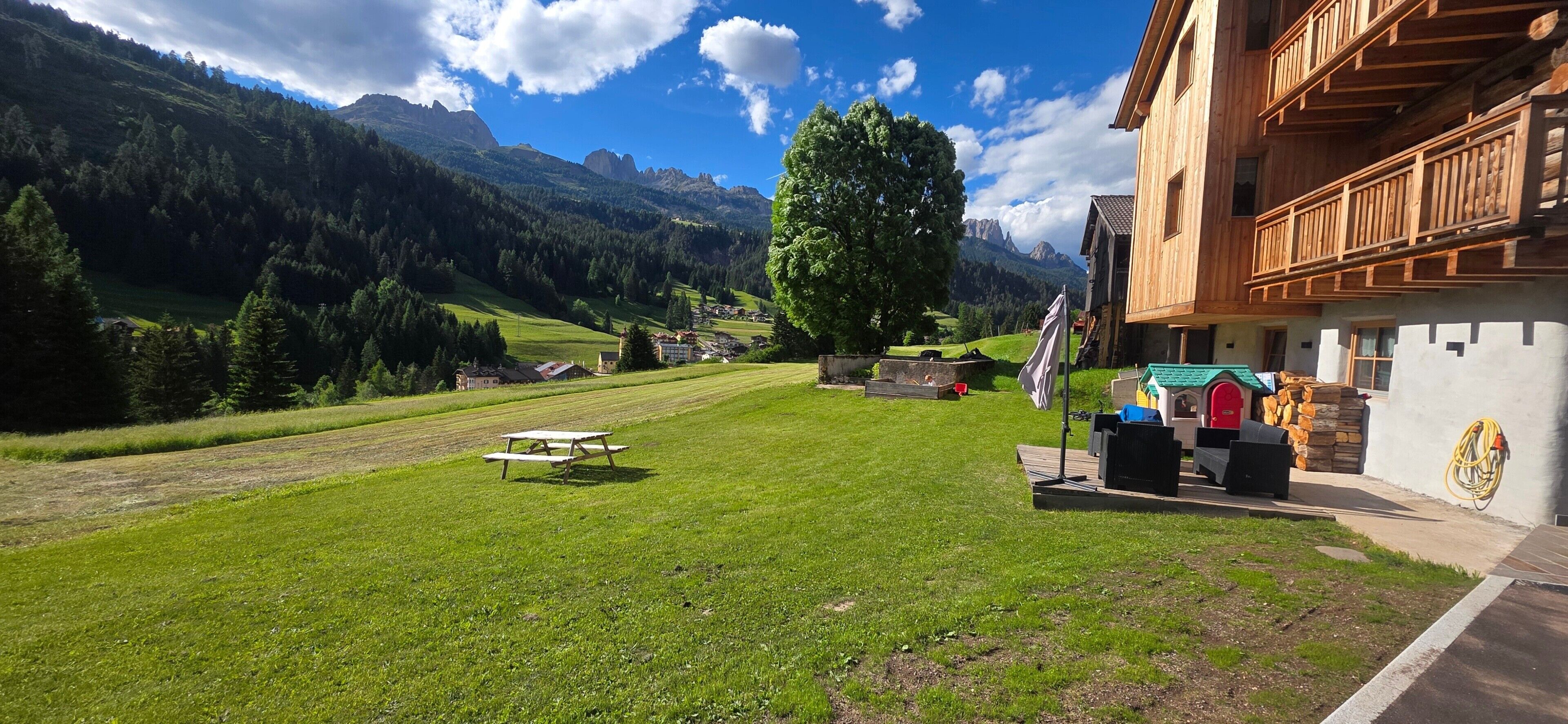 Vista de la montaña con un edificio de madera, una mesa de picnic y un gran árbol.