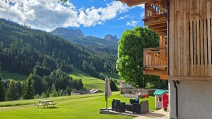 Une cabane en bois dotée d’un balcon donnant sur un paysage montagneux.