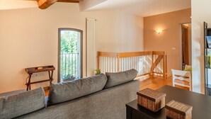 Una sala de estar con un sofá, una mesa con una cesta, un banco de madera y una escalera.