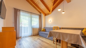 A room with a wooden ceiling, a sofa, a table, and a television.
