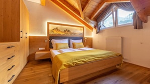 A bedroom with a wooden bed, a nightstand, a wardrobe, and a window with curtains.
