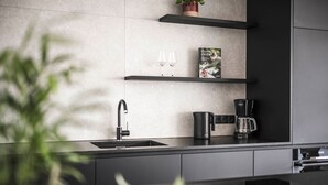 Una cocina moderna con un lavamanos integrado, una cafetera y una revista sobre la encimera.