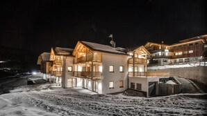 Un hotel a più piani con il terreno innevato, ampie finestre e un balcone.