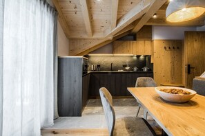 Une cuisine moderne avec des meubles en bois, une table à manger avec des chaises et une grande fenêtre.