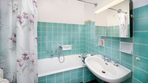 A bathroom with a bathtub, a sink, and a shower curtain with floral patterns. - Studio Apartment 'Spiess' with Mountain View, Shared Pool and Wi-Fi (Merano)