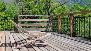 Une terrasse en bois avec deux chaises longues et une rambarde en bois.