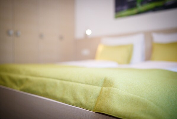 A hotel room with a bed, a headboard, and a wall-mounted light fixture.