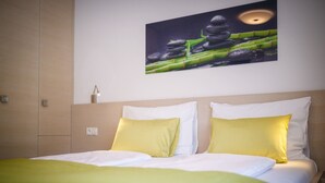Une chambre d’hôtel avec un lit, des oreillers, un tableau accroché au mur et une lampe de chevet.