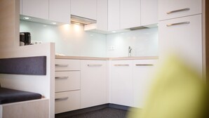 Une cuisine moderne avec des meubles blancs, un plan de travail et un four à micro-ondes encastré.