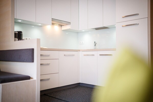 Une cuisine moderne avec des meubles blancs, un plan de travail et un four à micro-ondes encastré.