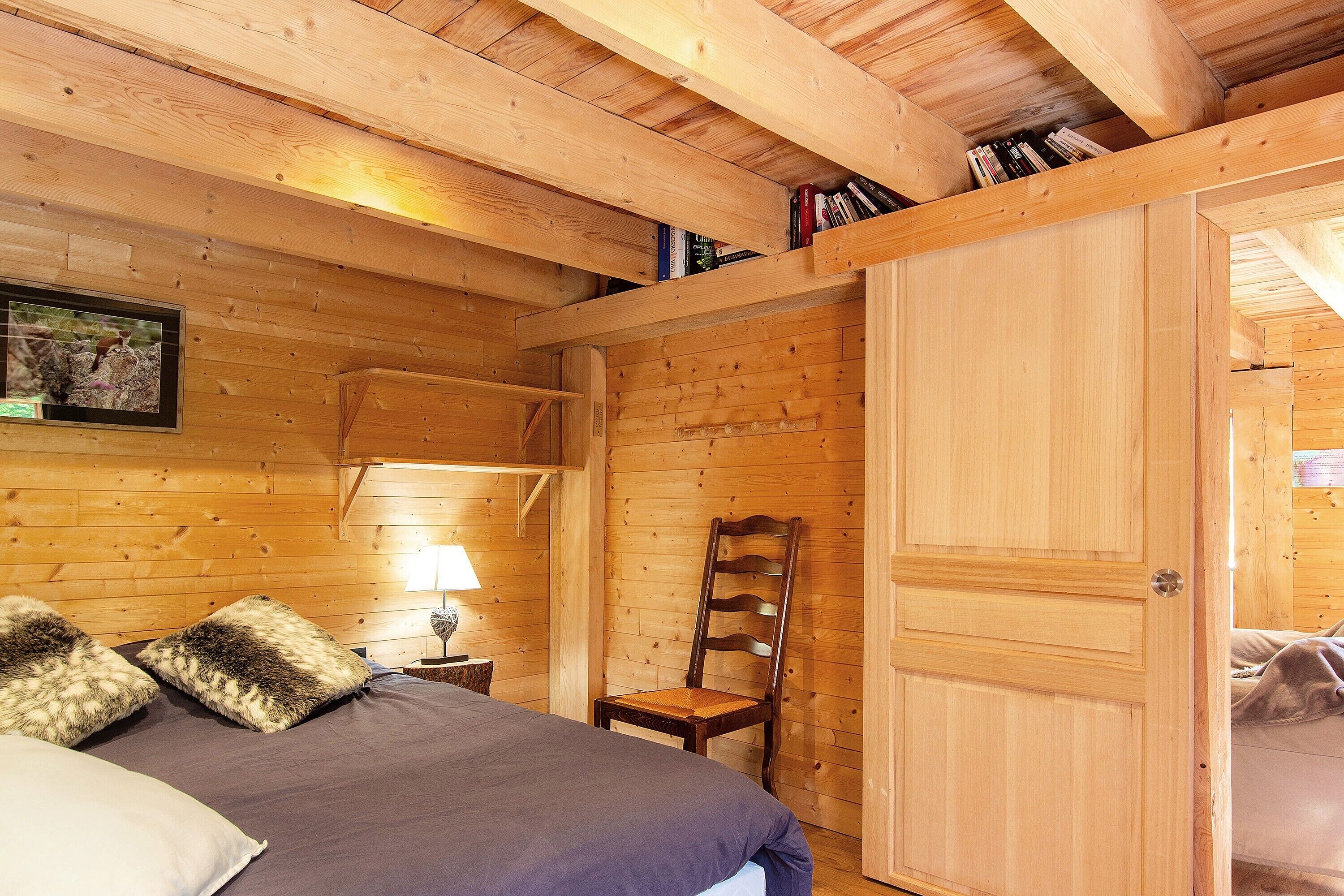 Un interno in legno con un letto, una sedia e una porta.