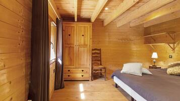 A wooden interior with a bed, a chair, and a wardrobe.