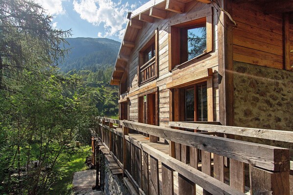 A wooden cabin with a balcony overlooking a forested valley.