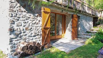 A stone building with a wooden door and a staircase leading up to a wooden deck.