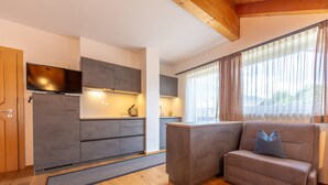 Une cuisine moderne dotée d’appareils électroménagers intégrés, un canapé avec un coussin et une fenêtre avec des rideaux.