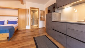 Une chambre moderne avec un lit, un plafond en bois et un coin cuisine équipé de placards et d’un plan de travail.